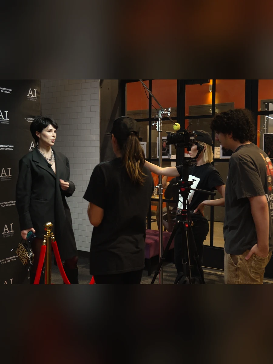 A crew filming an interview at the backdrop